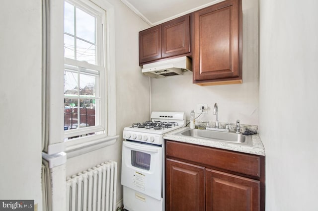 kitchen featuring under cabinet range hood, a sink, light countertops, radiator, and white gas range