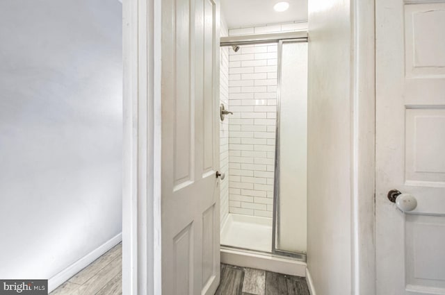 full bathroom with a shower stall, baseboards, and wood finished floors