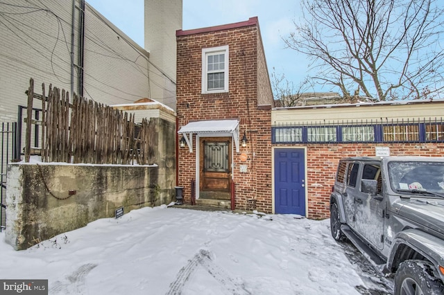 view of front of home with brick siding and fence