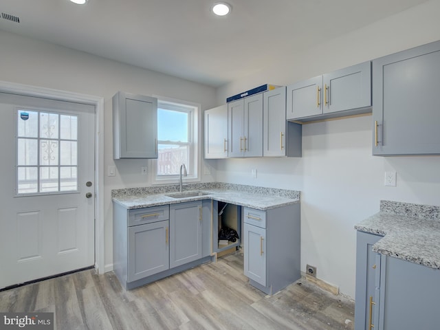 kitchen with gray cabinets, sink, a healthy amount of sunlight, and light hardwood / wood-style floors