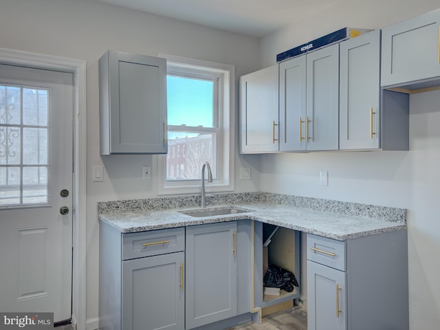 kitchen featuring light stone counters, plenty of natural light, gray cabinetry, and sink