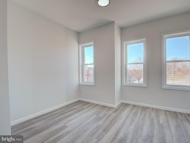 spare room with a wealth of natural light and light hardwood / wood-style flooring