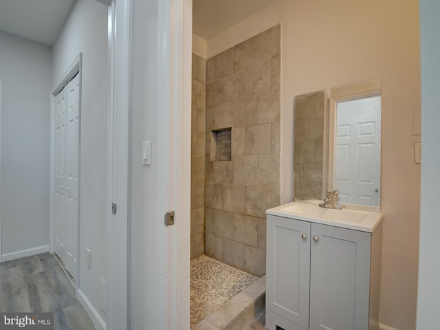 bathroom with hardwood / wood-style floors, vanity, and tiled shower