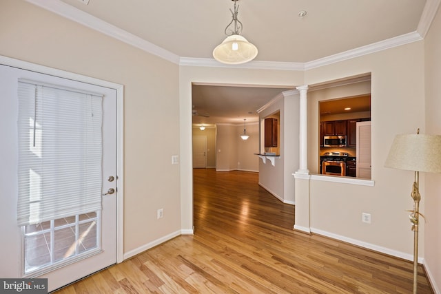 entryway with ornate columns, ornamental molding, and light hardwood / wood-style flooring