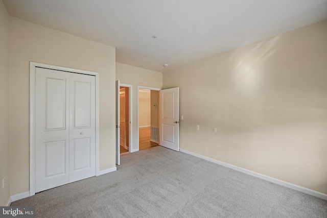 unfurnished bedroom with light colored carpet and a closet