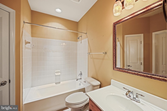 full bathroom featuring vanity, tiled shower / bath, and toilet