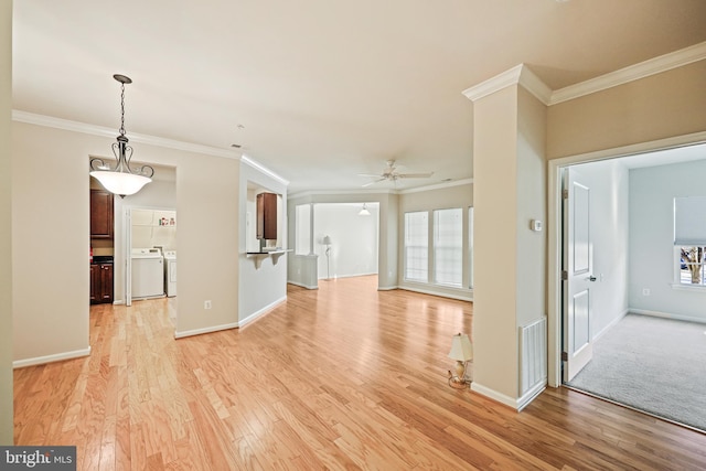 unfurnished living room with ornamental molding, washer and dryer, ceiling fan, and light hardwood / wood-style flooring