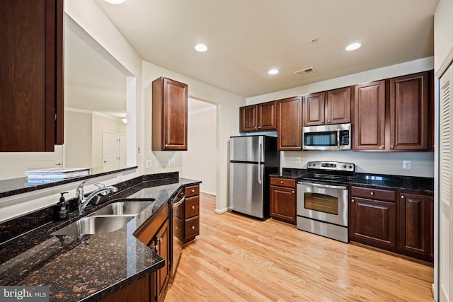 kitchen featuring stainless steel appliances, sink, dark stone countertops, and light hardwood / wood-style flooring