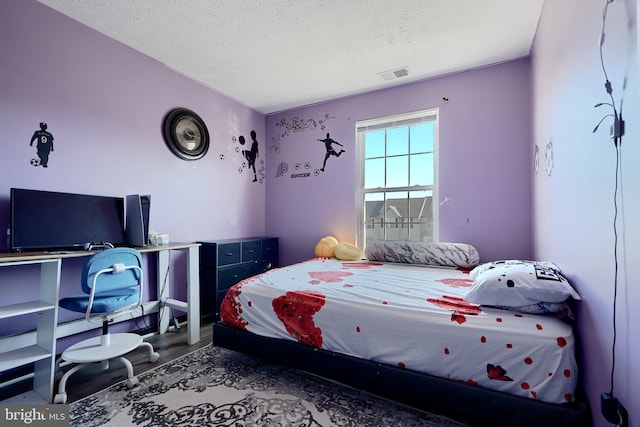 bedroom with hardwood / wood-style floors and a textured ceiling