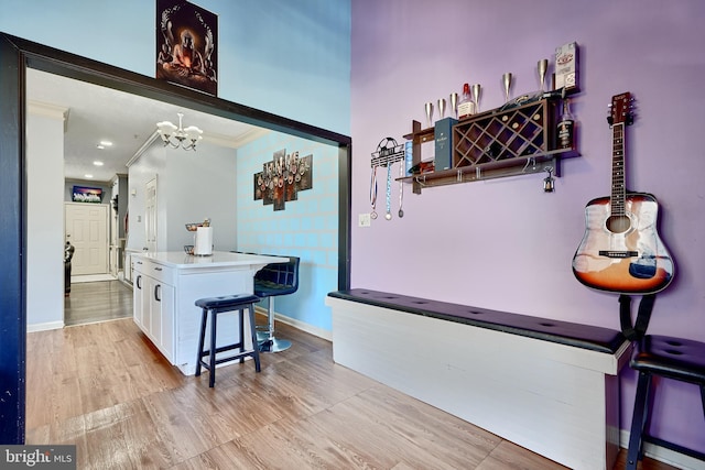 corridor with an inviting chandelier, ornamental molding, and light hardwood / wood-style flooring