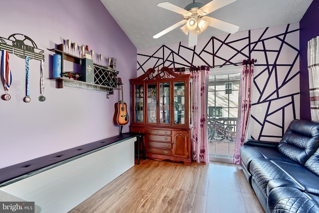 interior space featuring ceiling fan, high vaulted ceiling, a textured ceiling, and light wood-type flooring