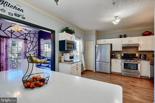 kitchen with white cabinets, light wood-type flooring, stainless steel appliances, and tasteful backsplash