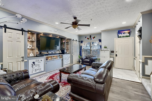 living room with hardwood / wood-style flooring, a barn door, crown molding, and a textured ceiling