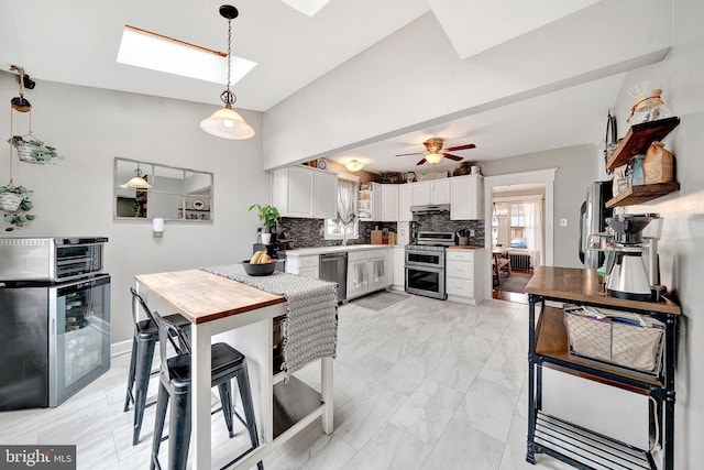 dining area featuring beverage cooler, marble finish floor, a skylight, and a ceiling fan