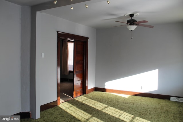 unfurnished room with dark carpet and ceiling fan