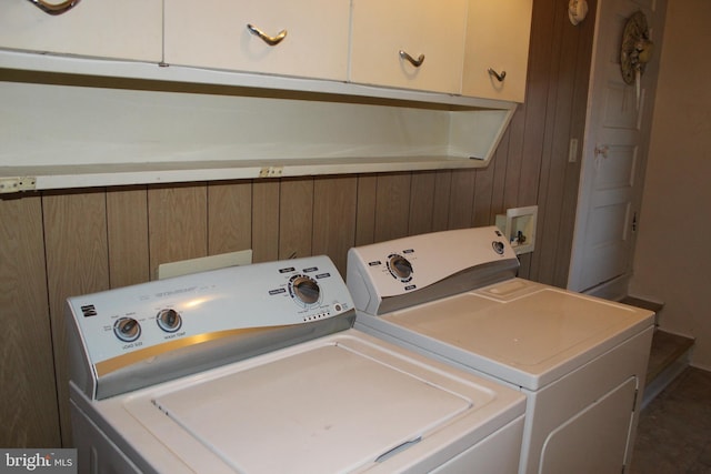 washroom with cabinets, wooden walls, and washer and dryer