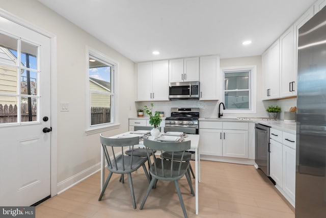 kitchen with white cabinetry, light hardwood / wood-style flooring, appliances with stainless steel finishes, and tasteful backsplash