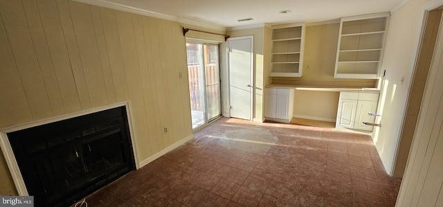 unfurnished living room featuring built in shelves, crown molding, and wood walls