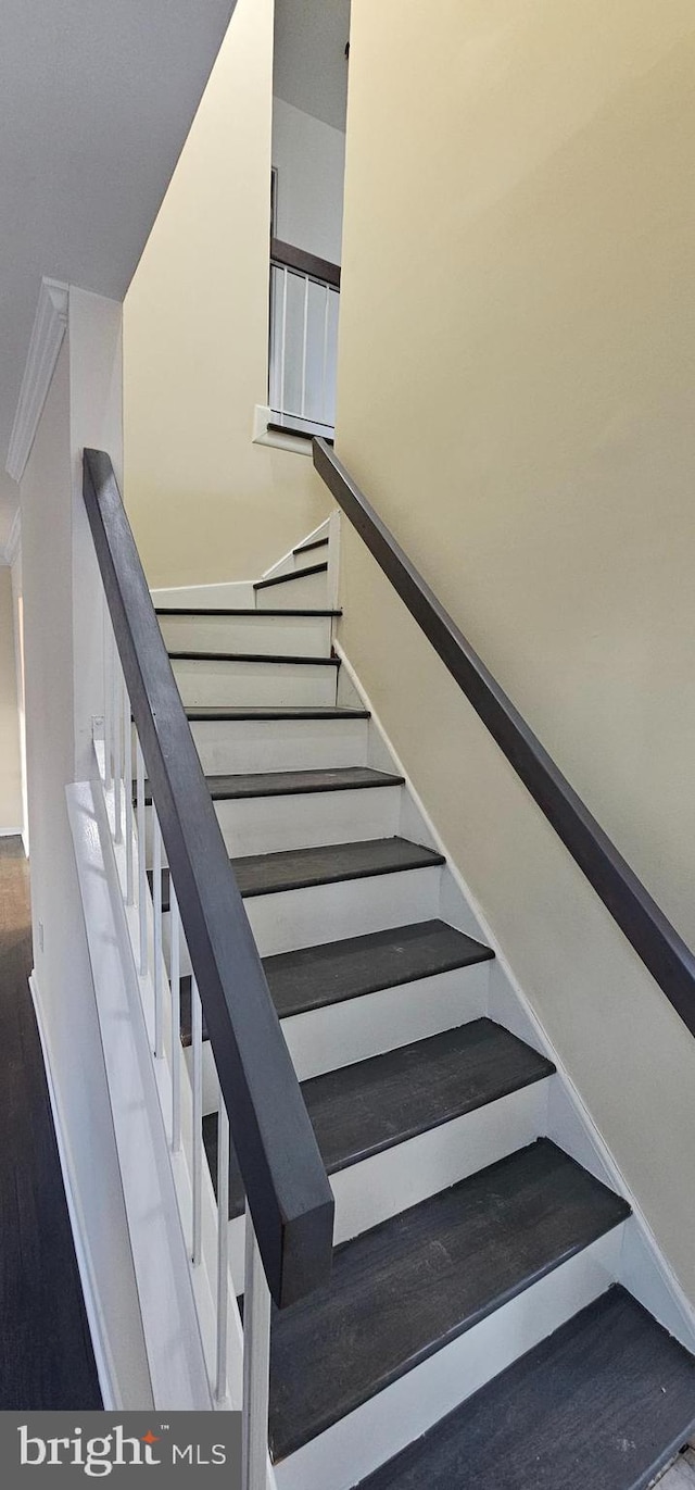 staircase with wood-type flooring and ornamental molding