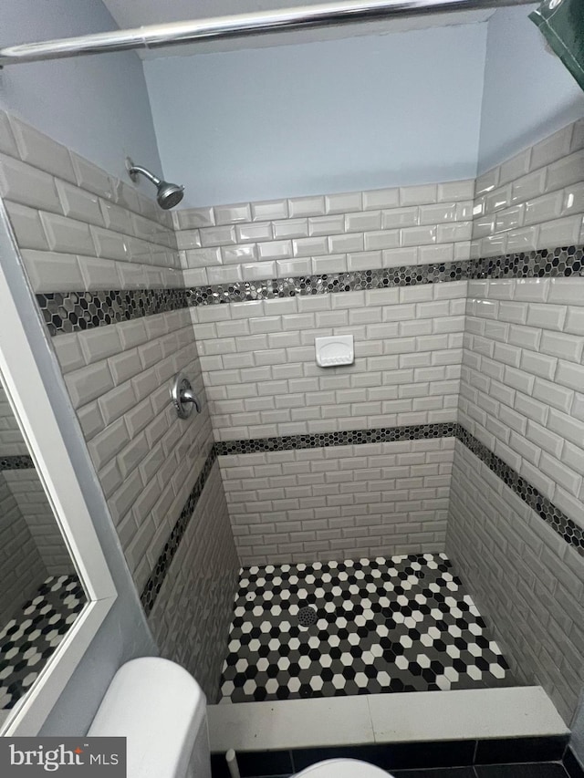 bathroom featuring tiled shower and toilet