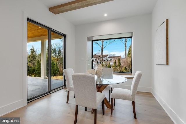 dining room featuring beamed ceiling and light hardwood / wood-style floors