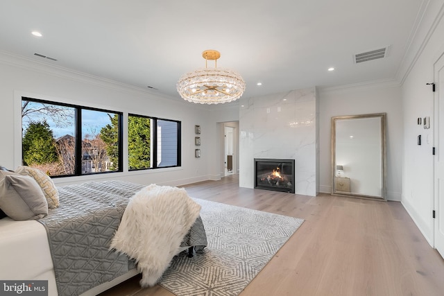 bedroom featuring crown molding, a fireplace, a chandelier, and light hardwood / wood-style flooring