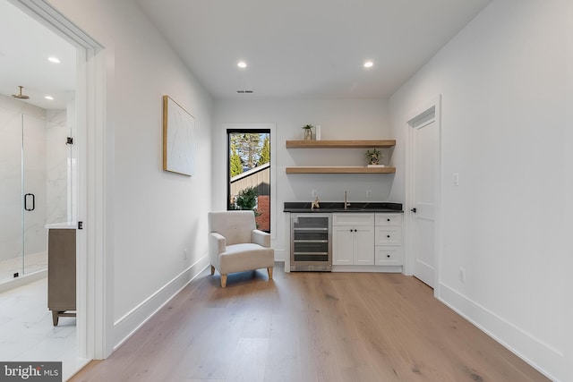 living area featuring light wood-type flooring, wine cooler, and wet bar