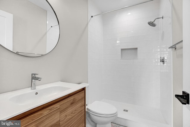 bathroom with tiled shower, vanity, and toilet