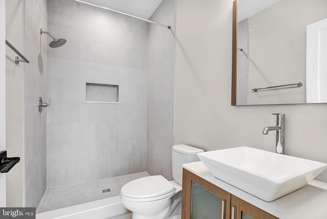 bathroom featuring tiled shower, vanity, and toilet