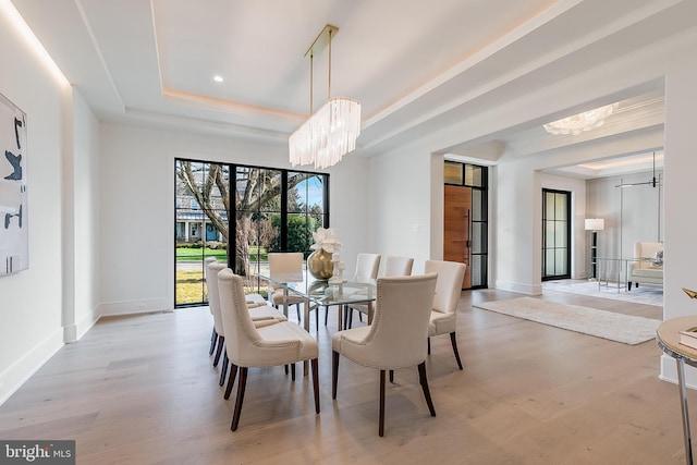 dining room featuring a tray ceiling, light hardwood / wood-style flooring, and a chandelier