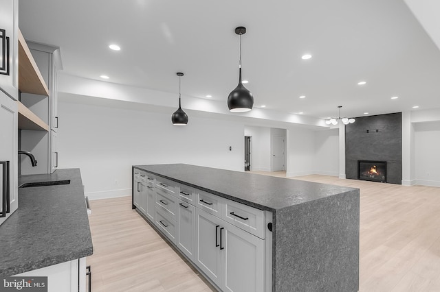 kitchen with a large fireplace, a kitchen island, hanging light fixtures, and sink