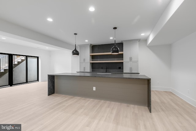 kitchen with gray cabinetry, sink, light hardwood / wood-style flooring, a kitchen island, and hanging light fixtures