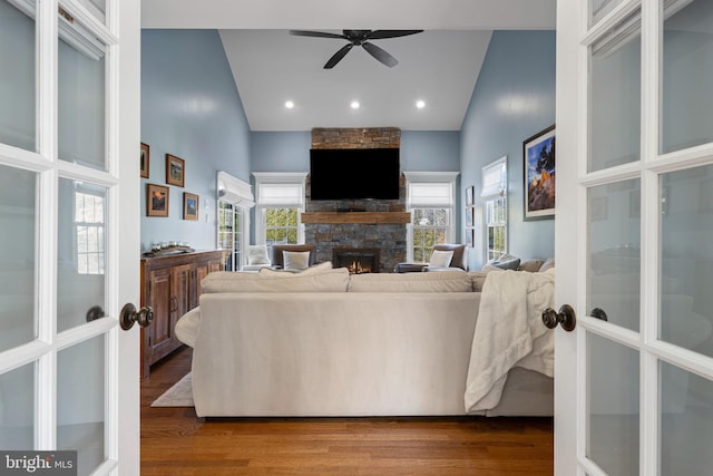 living room featuring hardwood / wood-style floors, french doors, a fireplace, high vaulted ceiling, and ceiling fan