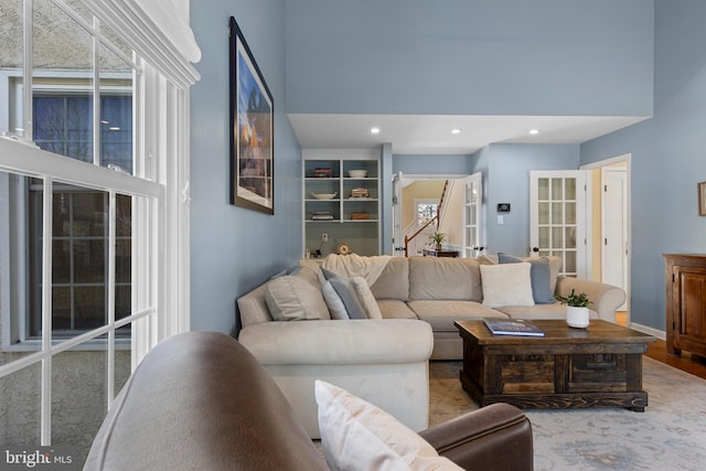 living room featuring french doors, a wealth of natural light, and a high ceiling