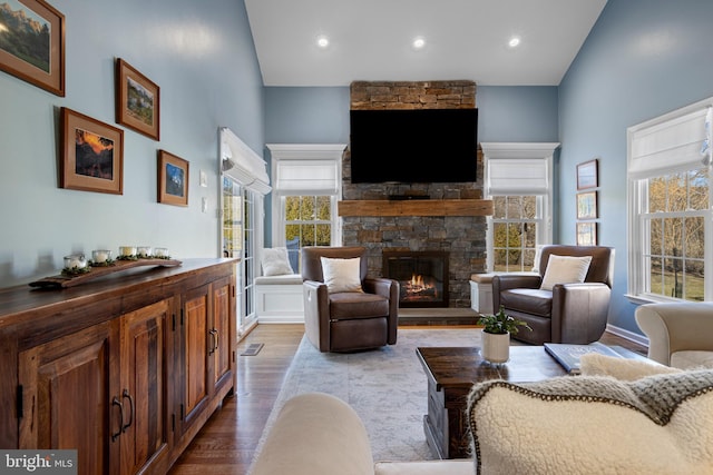 living room with light hardwood / wood-style floors, lofted ceiling, and a stone fireplace