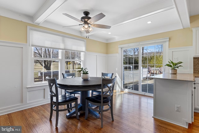 dining space with ceiling fan, hardwood / wood-style flooring, and beamed ceiling