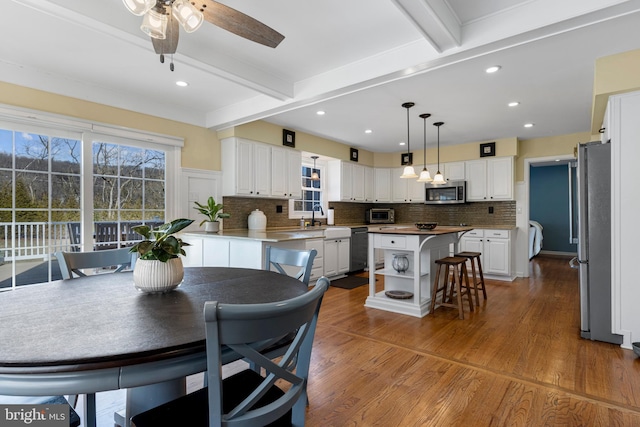 dining area with ceiling fan, hardwood / wood-style floors, and beamed ceiling