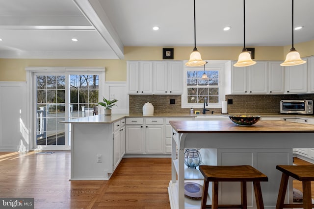 kitchen with white cabinetry, decorative light fixtures, butcher block countertops, and a kitchen island