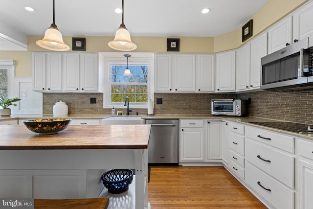 kitchen with hanging light fixtures, white cabinets, appliances with stainless steel finishes, and sink