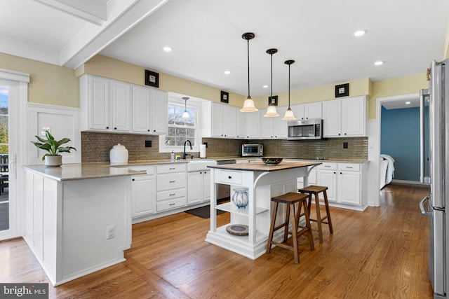 kitchen with sink, white cabinetry, appliances with stainless steel finishes, and kitchen peninsula