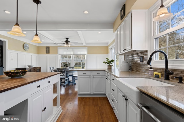 kitchen with beam ceiling, dishwasher, light stone counters, and white cabinetry