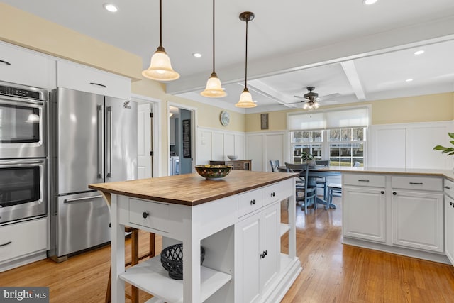 kitchen with white cabinetry, appliances with stainless steel finishes, beamed ceiling, decorative light fixtures, and a center island