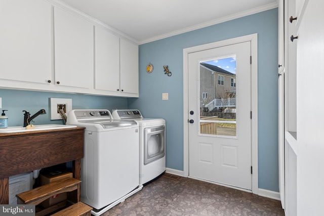 clothes washing area with washer and clothes dryer, crown molding, a healthy amount of sunlight, and cabinets