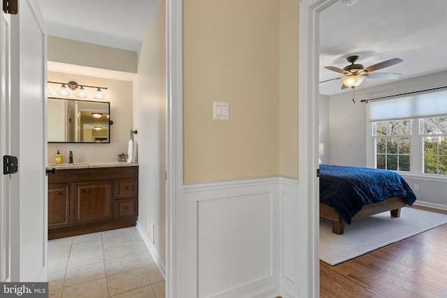 bedroom featuring ceiling fan, light hardwood / wood-style floors, and sink