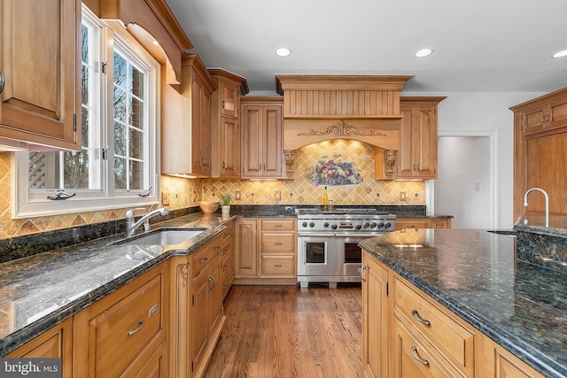 kitchen featuring dark hardwood / wood-style flooring, dark stone counters, double oven range, and sink