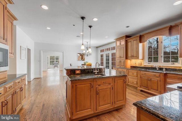 kitchen with sink, an inviting chandelier, a kitchen island with sink, and hanging light fixtures