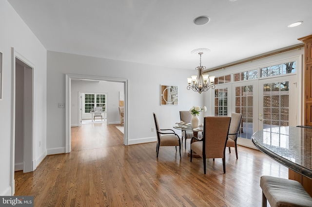 dining space featuring a notable chandelier, french doors, a wealth of natural light, and wood-type flooring