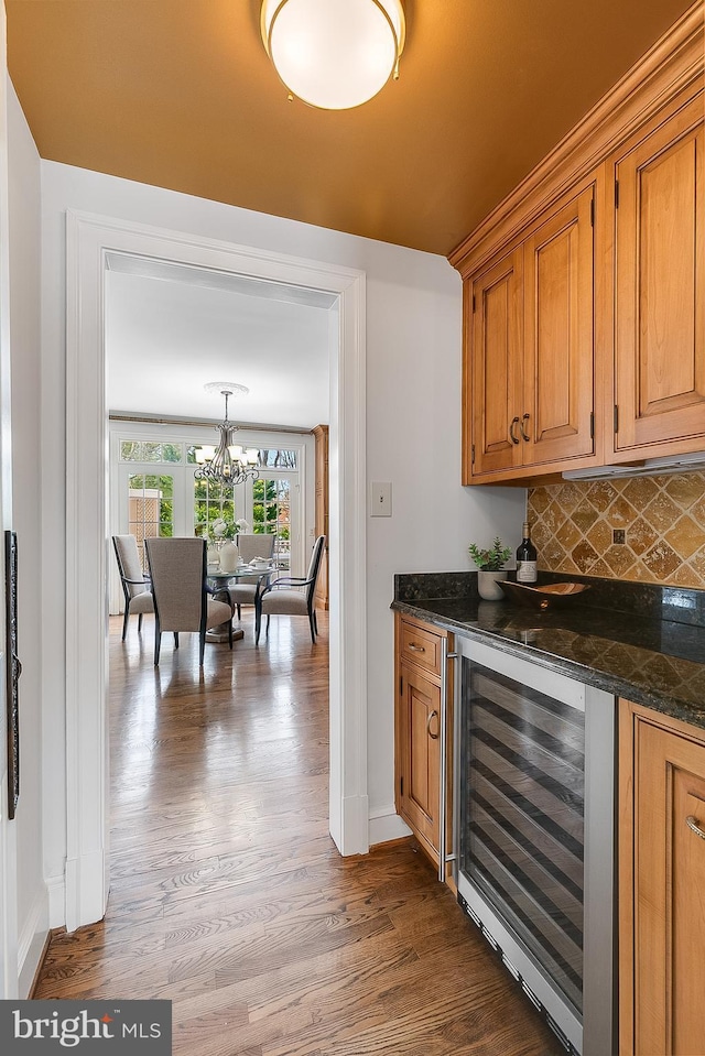 bar featuring decorative backsplash, an inviting chandelier, wine cooler, and light hardwood / wood-style flooring