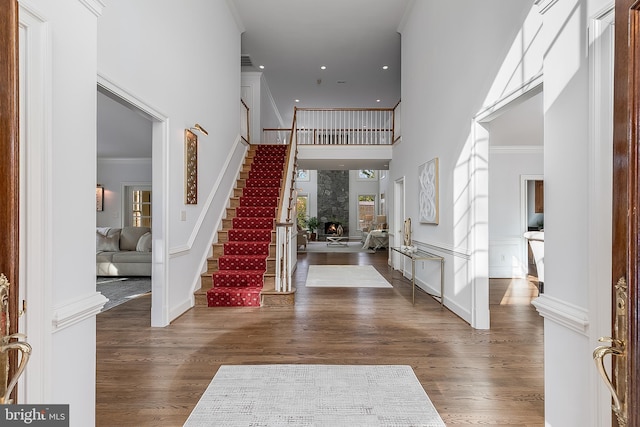 entrance foyer with a towering ceiling, crown molding, and dark hardwood / wood-style floors