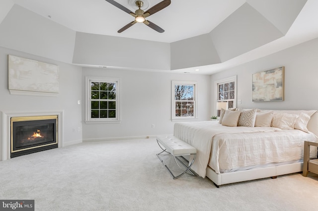 carpeted bedroom featuring ceiling fan, a high ceiling, and a tray ceiling